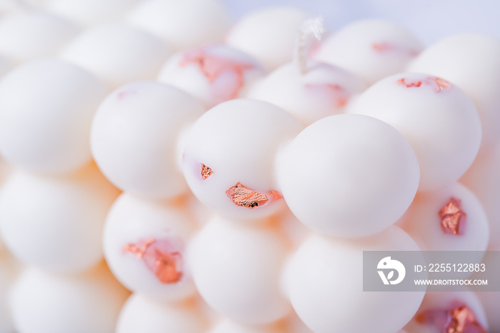 Close-up of white bubble cube candles with copper metal flakes, abstract background