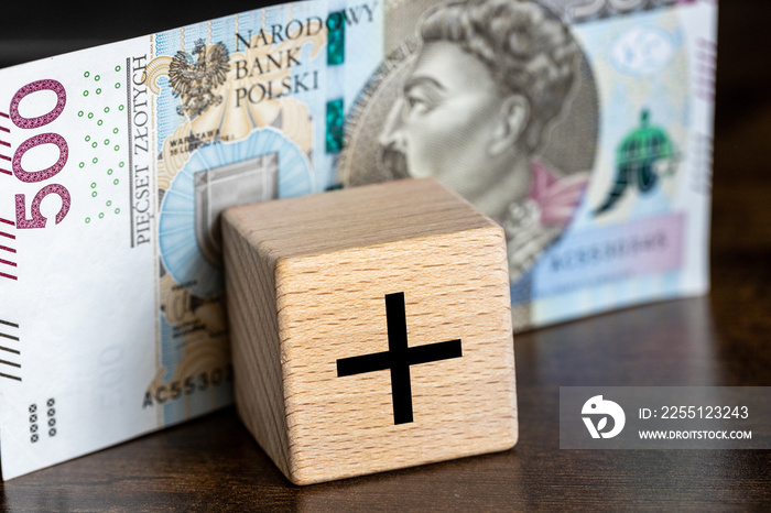 500 plus, Polish social program supporting financially citizens raising children, a five hundred zloty banknote and a children’s wooden block with the sign +