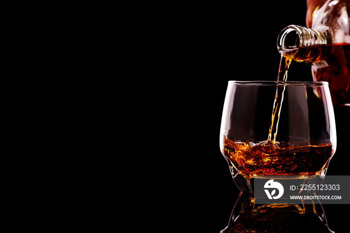 whiskey pouring in glasses with ice cubes isolated on black background. have space for text