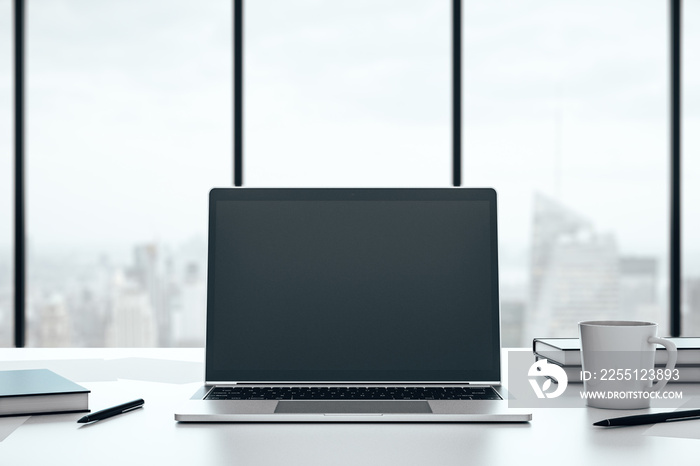 Front view of open laptop with blank screen on white desk with cup of coffee and large window with city view. Mock up. 3D Rendering