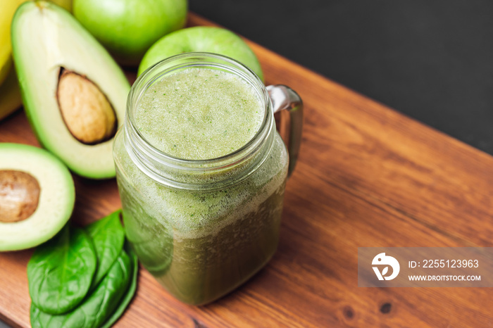 Green smoothie drink blended in a glass jar, avocado, spinach leaves and apples at wooden board