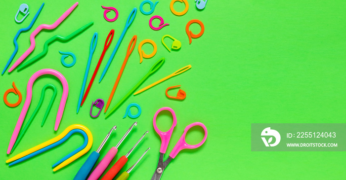 Knitting tools on a yellow background. Crochet hooks scissors, plastic knitting nedles, markers, curved needles. Flat lay.