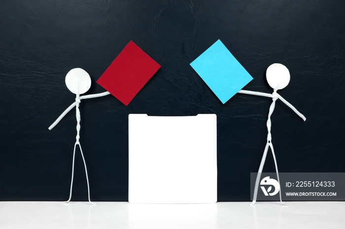 Stick man figures holding red and blue paper ballot beside a vote box. US presidential election democrat versus republican. Dark background with copy space.