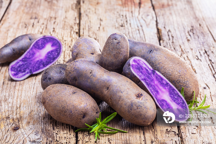 Vitolette noir or purple potato. On a wooden background.