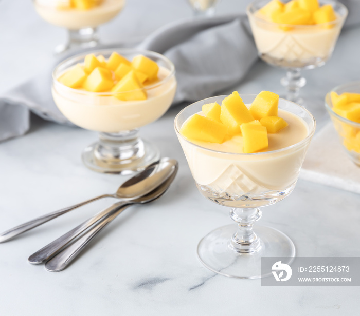 Close up of mango mousse dessert parfaits on a marble table against a light background.