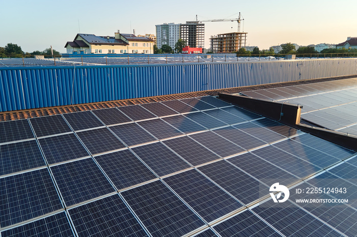 Aerial view of blue photovoltaic solar panels mounted on industrial building roof for producing green ecological electricity. Production of sustainable energy concept