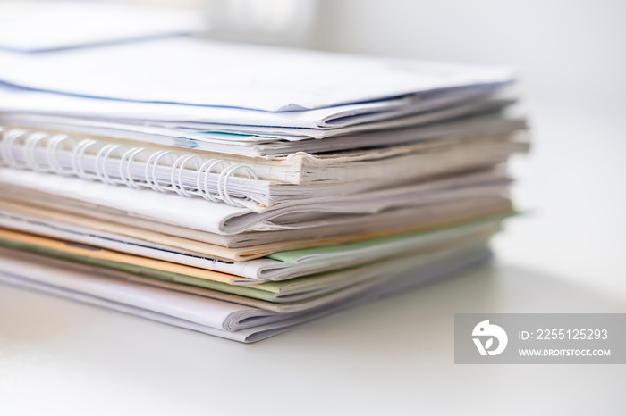 Pile of different notebooks on a white windowsill, in natural light from the window.