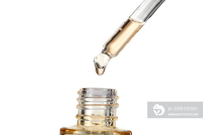 Part of a bottle with yellow cosmetic serum. Cosmetic glass pipette with a yellow oily drop of serum close-up on a white background.