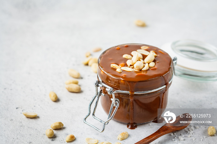 Homemade salted caramel with nuts in glass jar, copy space. Ingredient for cake snickers.