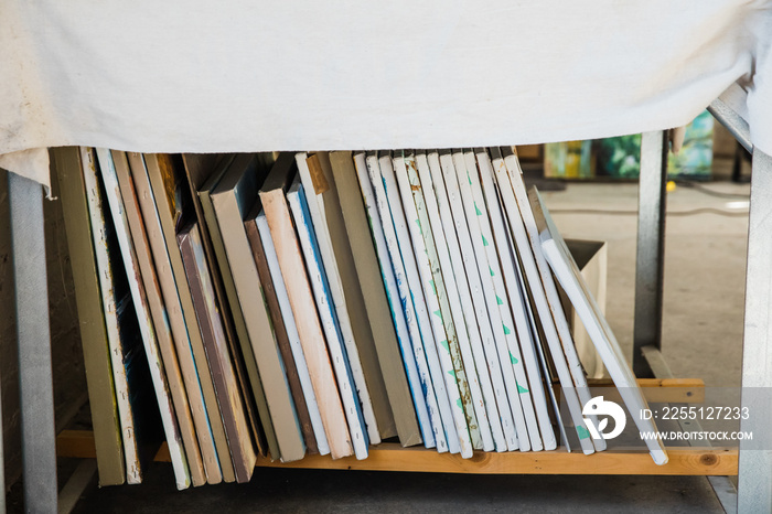 a vertical stack of painted canvases in an artist’s loft workspace