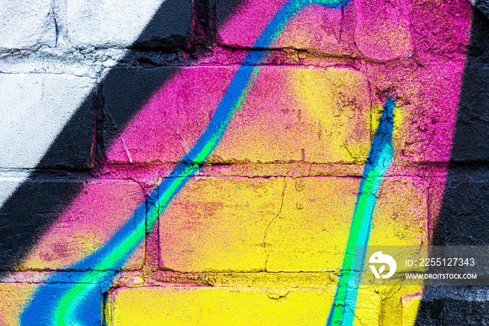 A fragment of colorful graffiti painted on a brick wall. Abstract backdrop for design.