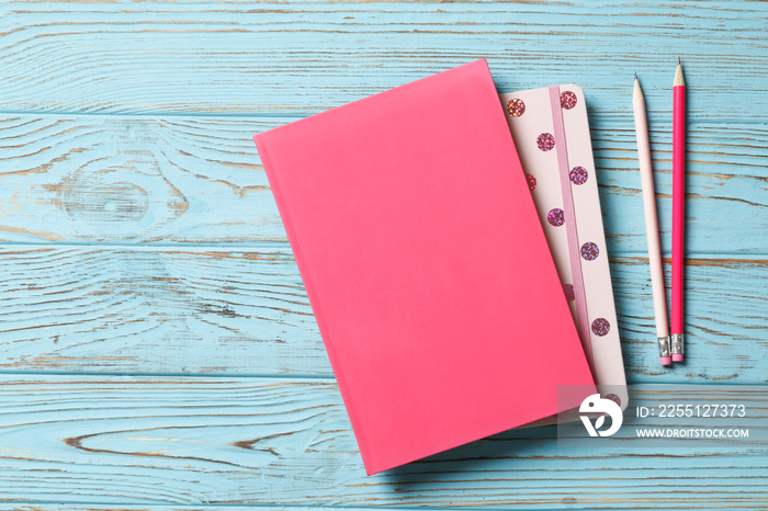 Pink pencil with notebook on a blue wooden background. Place for text