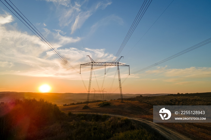 Dark silhouette of high voltage tower with electric power lines at sunrise. Transmission of electric energy concept