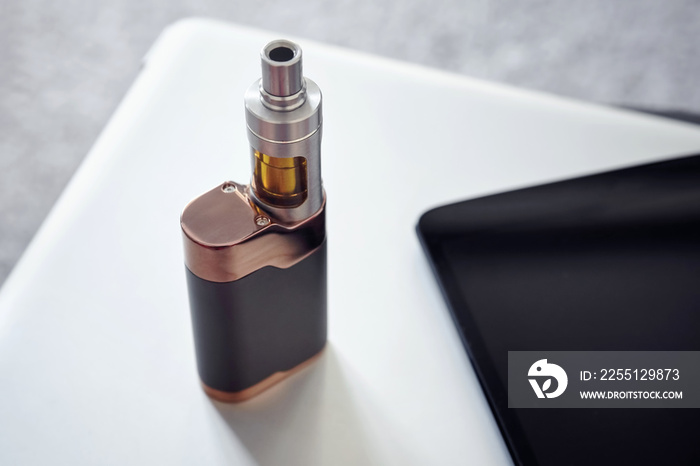 Close up view of an electronic cigarette on a table next to a tablet pc