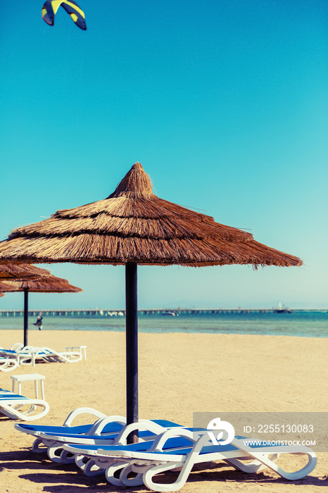 Beach with straw umbrellas and sunbeds. Egyptian resort in Sharm el Sheikh. Vacation concept.