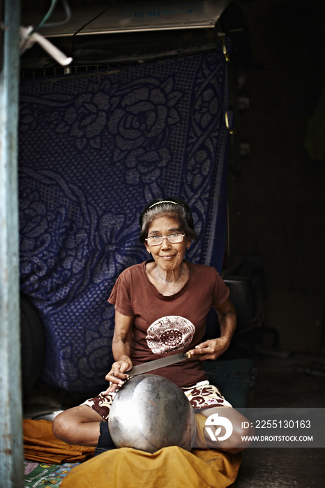 Older woman making metal bowl