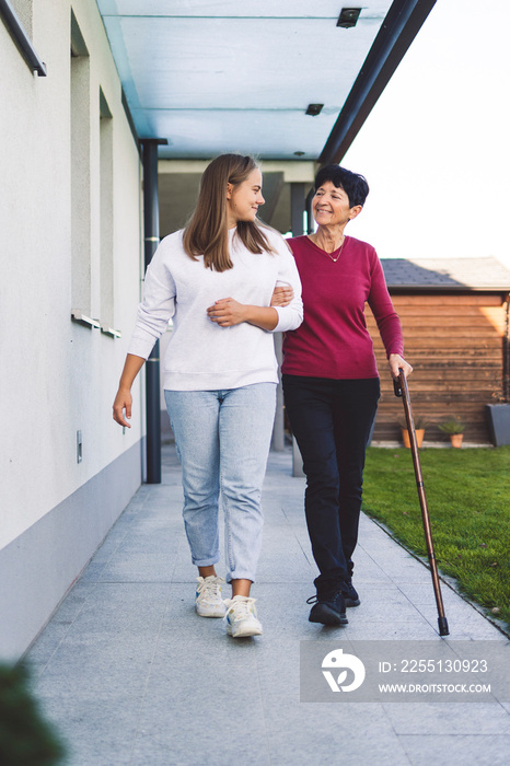 Vertical portrait of a nurse and senior woman holding hand in hand, nurse giving support to the elderly lady while she walks