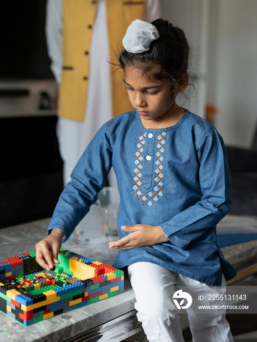 Boy (6-7) in traditional clothing playing with toy blocks