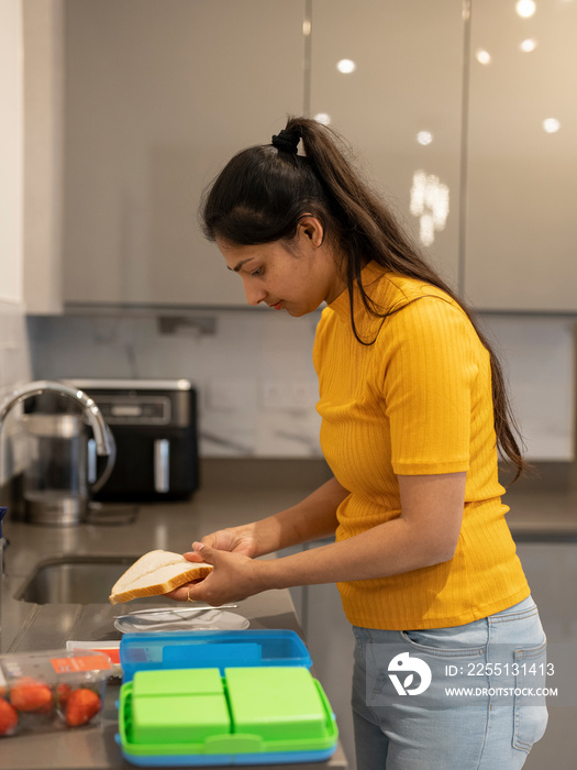 Young woman preparing lunch boxes in kitchen