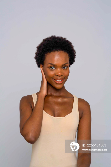 Studio portrait of smiling woman in cream colored tank top