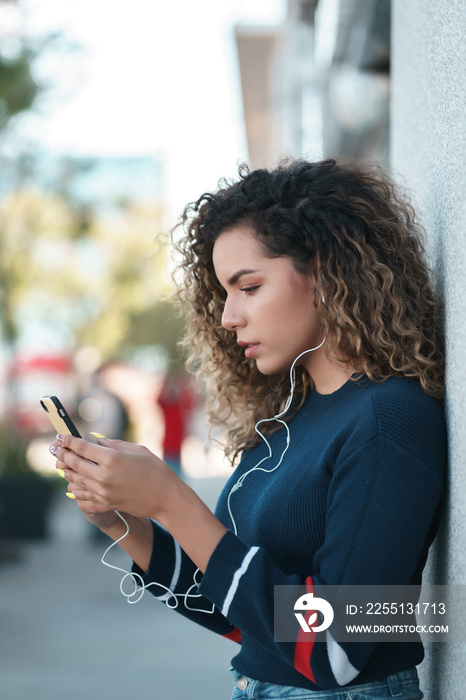 Young woman using her mobile phone outdoors on the street.