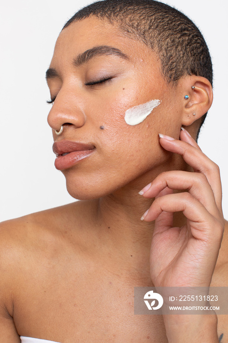 Studio portrait of woman face cream on cheek