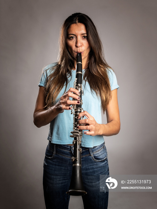 woman playing a clarinet on a gray background