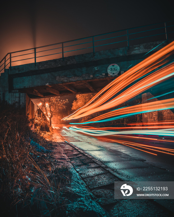 Traffic light trails at night under a viaduct