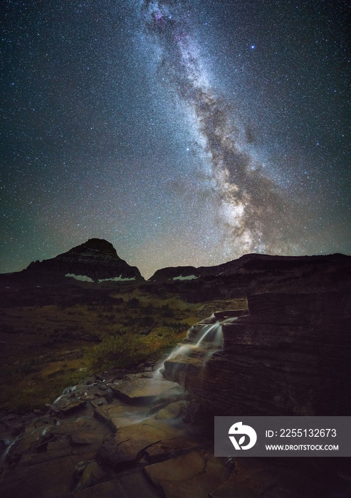 Small waterfall at glacier national park at night with milky way