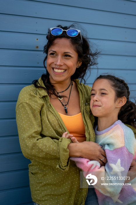 Smiling mother and daughter (8-9) hugging outdoors