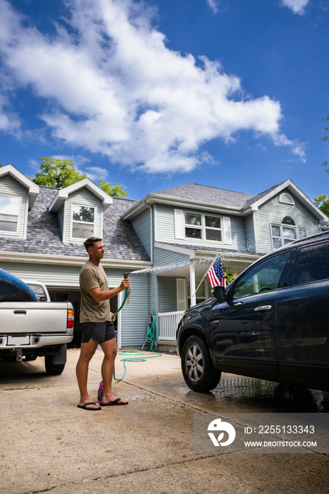 Air Force service member washes his vehicles with his sons in the driveway.