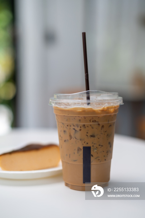 A glass of iced coffee with cheesecake on white table