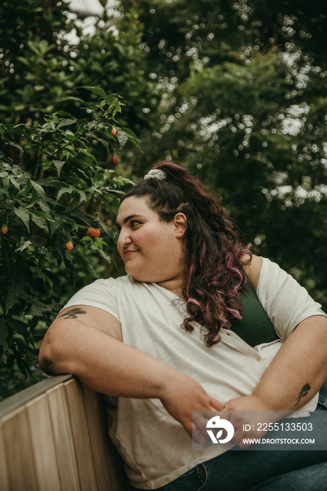 close up of plus size woman sitting on bench surrounded by plants