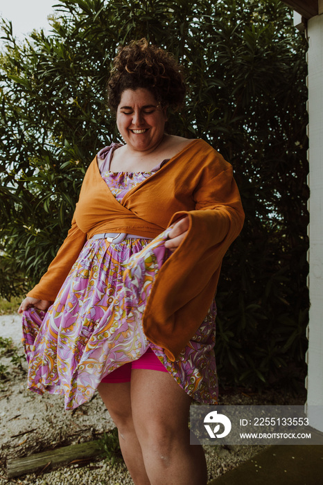 plus size woman dances outside with dress and bike shorts