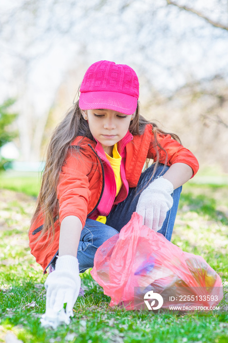 Young girl scavenge trash in the summer park. Volunteer and ecology concept