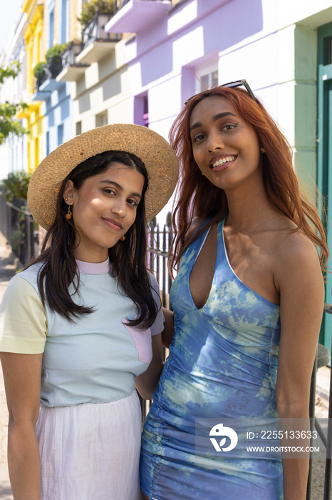 Portrait of smiling young women in summer clothes standing in street