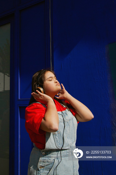 Young curvy woman with Down Syndrome listening to music