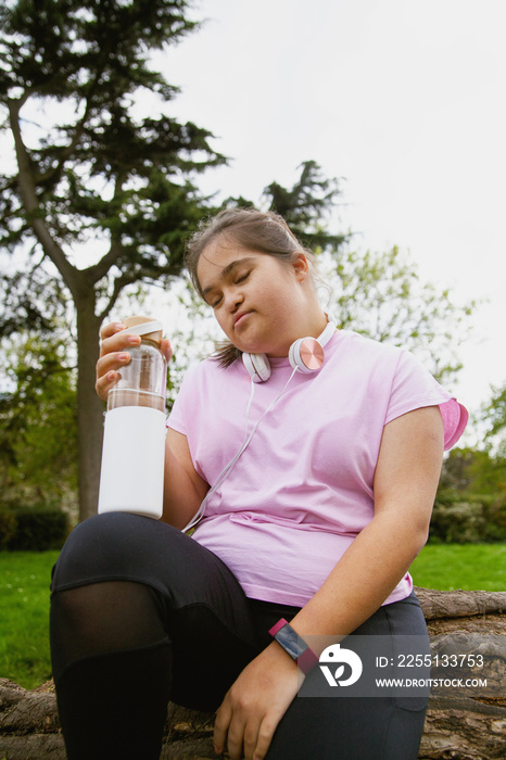 Young curvy girl with Down Syndrome holding reusable water bottle after workout