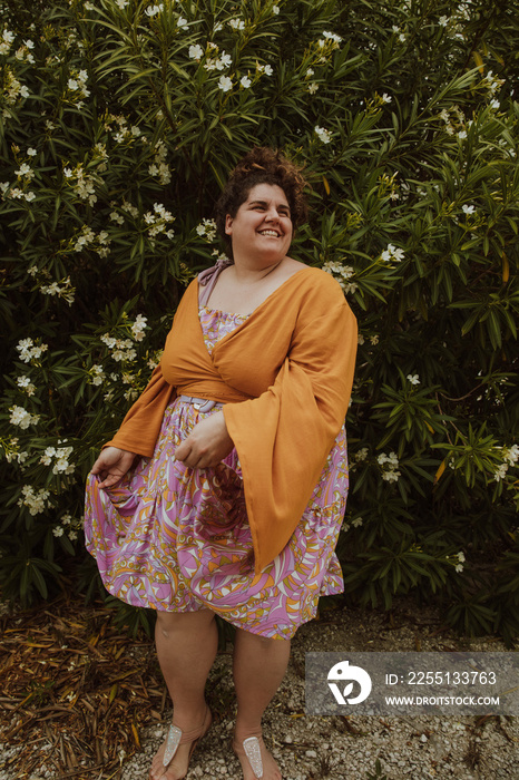 plus size woman dances in front of flowering bush