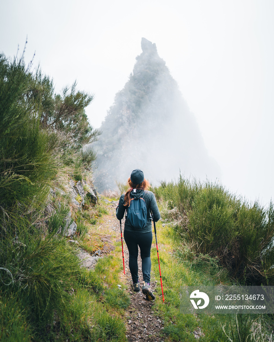 A young adventurous woman traveling and hiking alone in the mountains of Madeira in Portugal. High quality photo