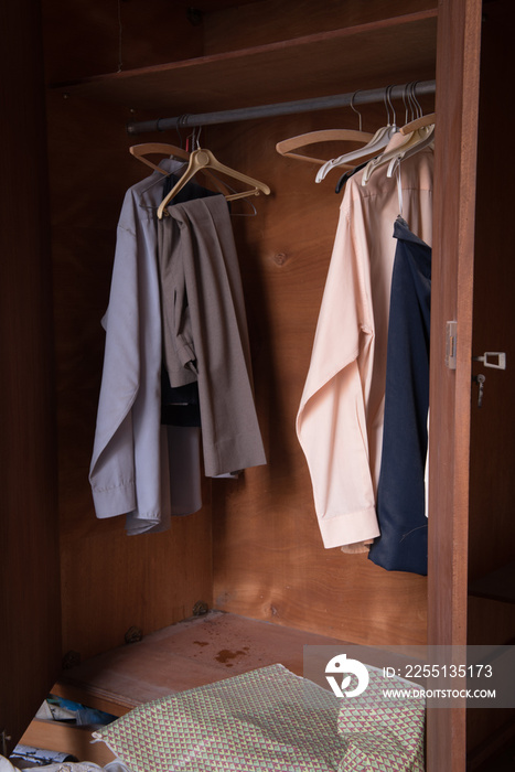 Abandoned messy bedroom with old used clothing on the ground and on the wardrobes.