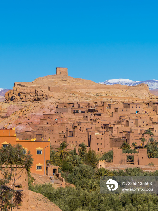Vertical view of clay houses and the Kasbah (fortress) in the ancient town of Aid Benhaddou, Morocco with Atlas mountains in the background
