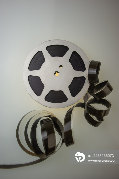 Aluminum reel with 16mm film on a colored background, close-up.