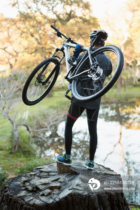 Male mountain biker carrying bicycle looking at nature