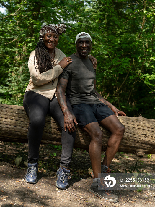 Portrait of mature couple sitting on log on hike