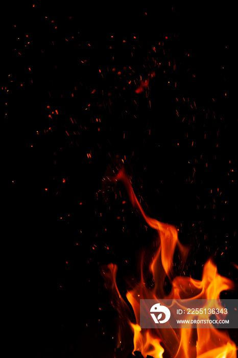 Fiery flame with sparks on a black background. Texture (element) for barbecue or cooking.