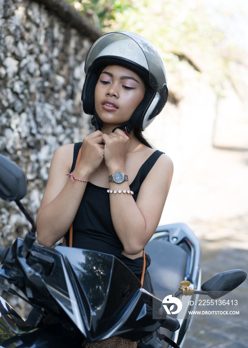 Asian girl; in a black dress on a scooter. Beautiful Balinese women lifestyle portrait