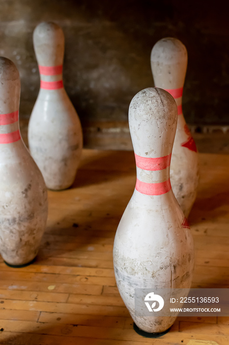 Vintage bowling pins set up in bowling alley. Bowling pins are old and weathered and show signs of aging.