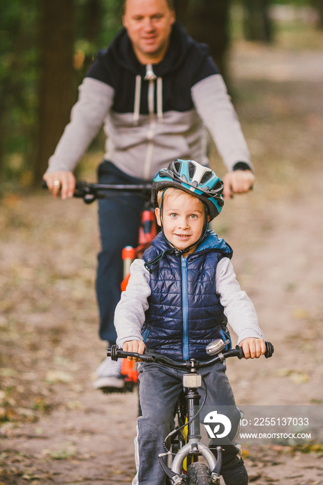 parents and kids cycling on forest trail. family in warm clothes cycling autumn park. Family mountain bike on forest. active sports outdoor recreation. Portrait Family Cycling Through Fall Woodland