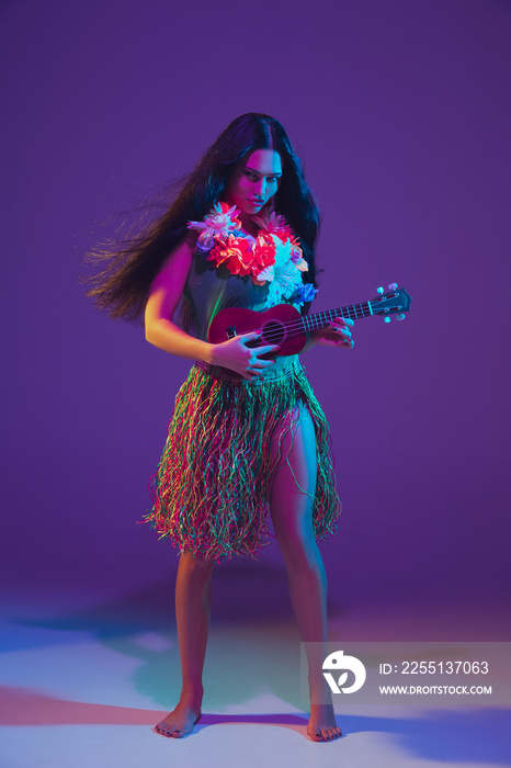 Fabulous Cinco de Mayo female dancer on purple studio background in neon light. Beautiful female model with ukulele, Mexico, Hawaii style. Celebration, holiday, music, beauty and fashion concept.